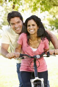 Young Hispanic Couple Cycling In Park