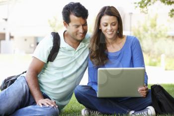 Man and woman using laptop outdoors