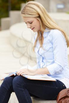 Teenage student reading outdoors