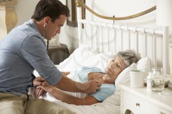 Doctor Examining Senior Female Patient In Bed At Home