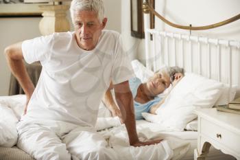 Senior Man Suffering From Backache Getting Out Of Bed