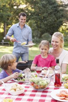 Family Enjoying Barbeque In Garden Together
