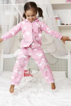 Young Girl Wearing Pajamas Jumping On Bed