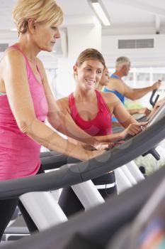 Woman On Running Machine In Gym Encouraged By Personal Trainer