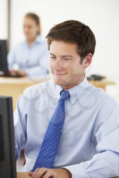 Businessman Working At Desk In Busy Office