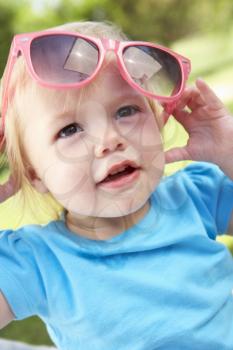 Female Toddler Trying To Put On Sunglasses