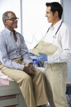 Doctor In Surgery With Male Patient Reading Notes
