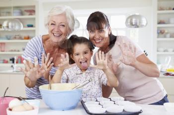Grandmother, Granddaughter And Mother Baking Cake In Kitchen