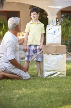 Grandfather And Grandson Building Model Robot In Garden