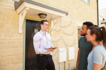 Young couple viewing a house with male real estate agent