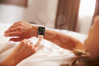 Woman Lying in Bed Whilst Checking News App on Smart Watch