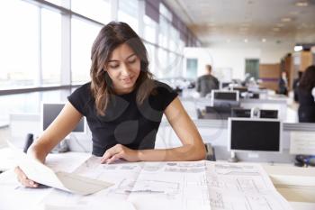 Young female architect working with blueprints in an office