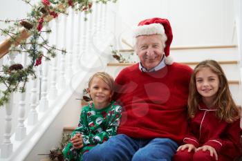 Grandfather With Grandchildren Sits On Stairs At Christmas