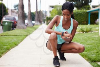 Young woman checking smart watch in the street before a run