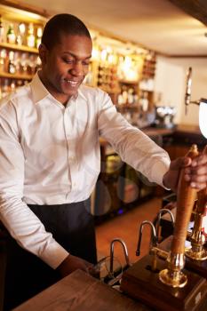 A young black man working behind a bar preparing drinks