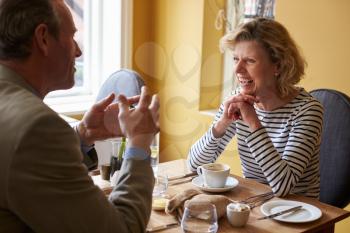 Senior couple talking over coffee and food at a restaurant
