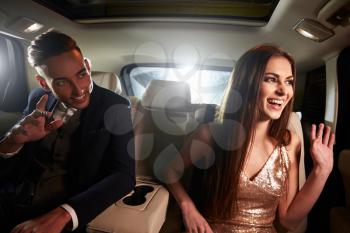 Young couple in the back of a limo looking out of the window