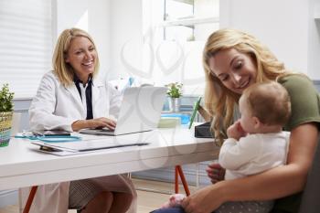 Mother And Baby Meeting With Female Doctor In Office