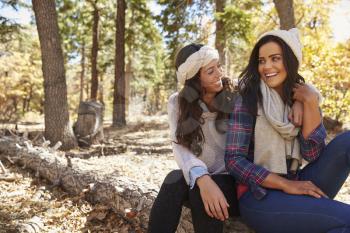 Lesbian couple sitting in a forest, looking at each other