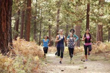 Group of young adult women running in a forest