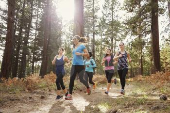 Group of young adult women running in a forest, close up