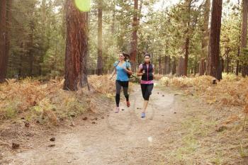 Two young women running in a forest