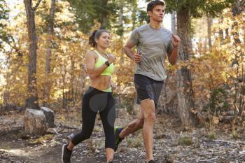 Caucasian woman and man running on a forest trail, close up