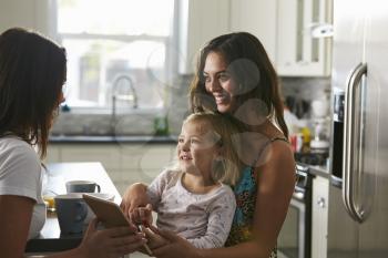 Female couple talking in the kitchen with their daughter