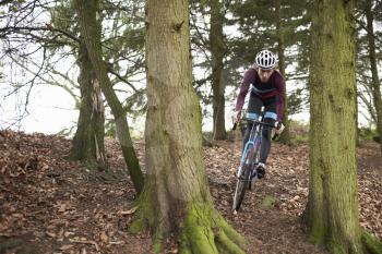 Cross-country cyclist riding between trees, front view