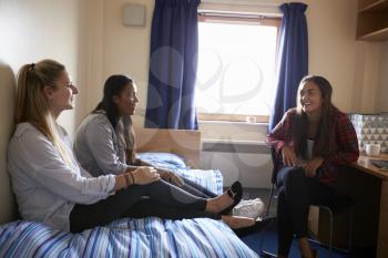 Female Students Relaxing In Bedroom Of Campus Accommodation