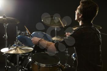 Rear View Of Drummer Playing Drum Kit In Studio