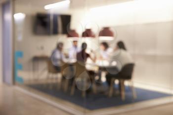 Corporate business team at table in a meeting room cubicle, defocussed
