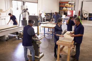Carpenters Working On Machines In Busy Woodworking Workshop