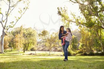 Asian Caucasian woman carrying her young daughter in a park