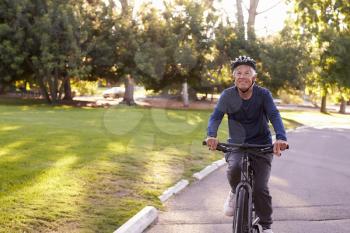 Front View Of Senior Man Cycling Through Park