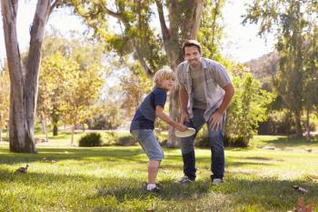 Father Teaching Son To Throw Frisbee In Park