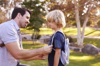 Father Fastening Son's Backpack As They Get Ready For Hike