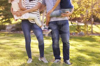 Parents Carrying Son And Daughter As They Play In Park