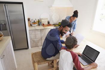 Parents helping kids with homework in kitchen, elevated view