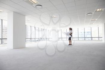 Female Architect In Modern Empty Office Looking At Plans