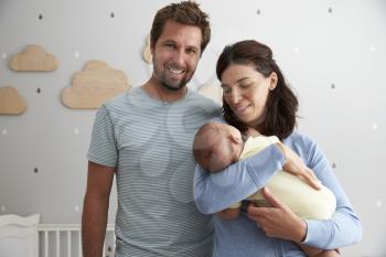 Portrait Of Parents With Newborn Son In Nursery