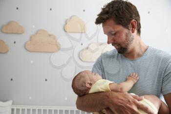 Father Comforting Newborn Baby Son In Nursery