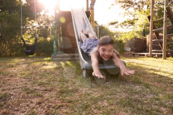 Portrait Of Girl Playing Outdoors At Home On Garden Slide
