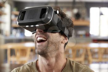 Man Sitting On Sofa Wearing Virtual Reality Headset
