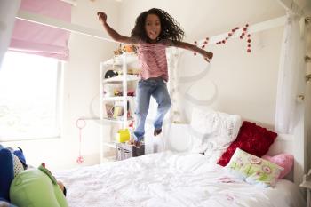 Young Girl Having Fun Jumping On Bed In Bedroom