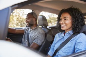 Young black couple in car on a road trip look ahead smiling