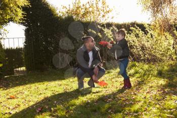 Boy And Father Playing With Autumn Leaves in Garden