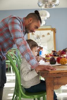 Father And Son Decorating Halloween Pumpkins At Home