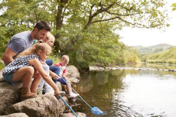 Family Fishing With Nets In River In UK Lake District