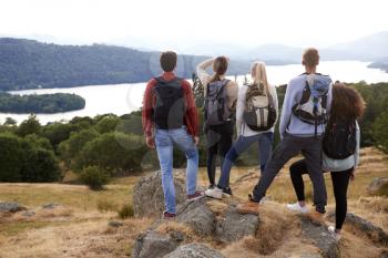 A group of five mixed race young adult friends admire the view after arriving at summit after a mountain hike, back view, close up